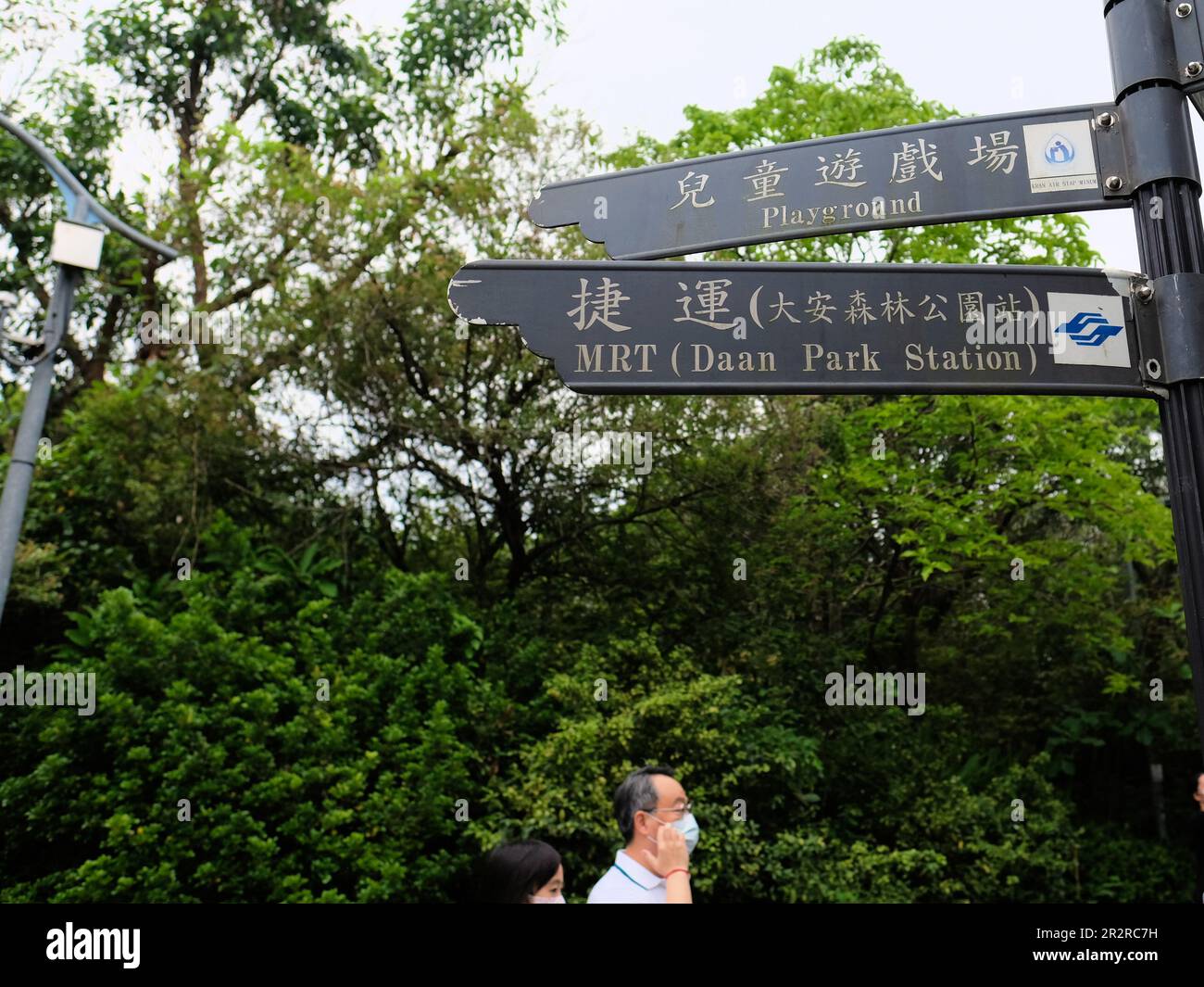 Bilingual Chinese English sign at Daan Park pointing towards playground and MRT station; Taipei, Taiwan. Stock Photo