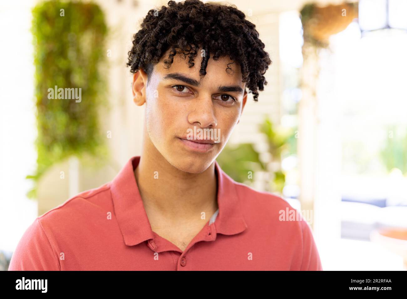 Close-up of biracial young man with dreadlocks looking at camera seriously at home, copy space Stock Photo