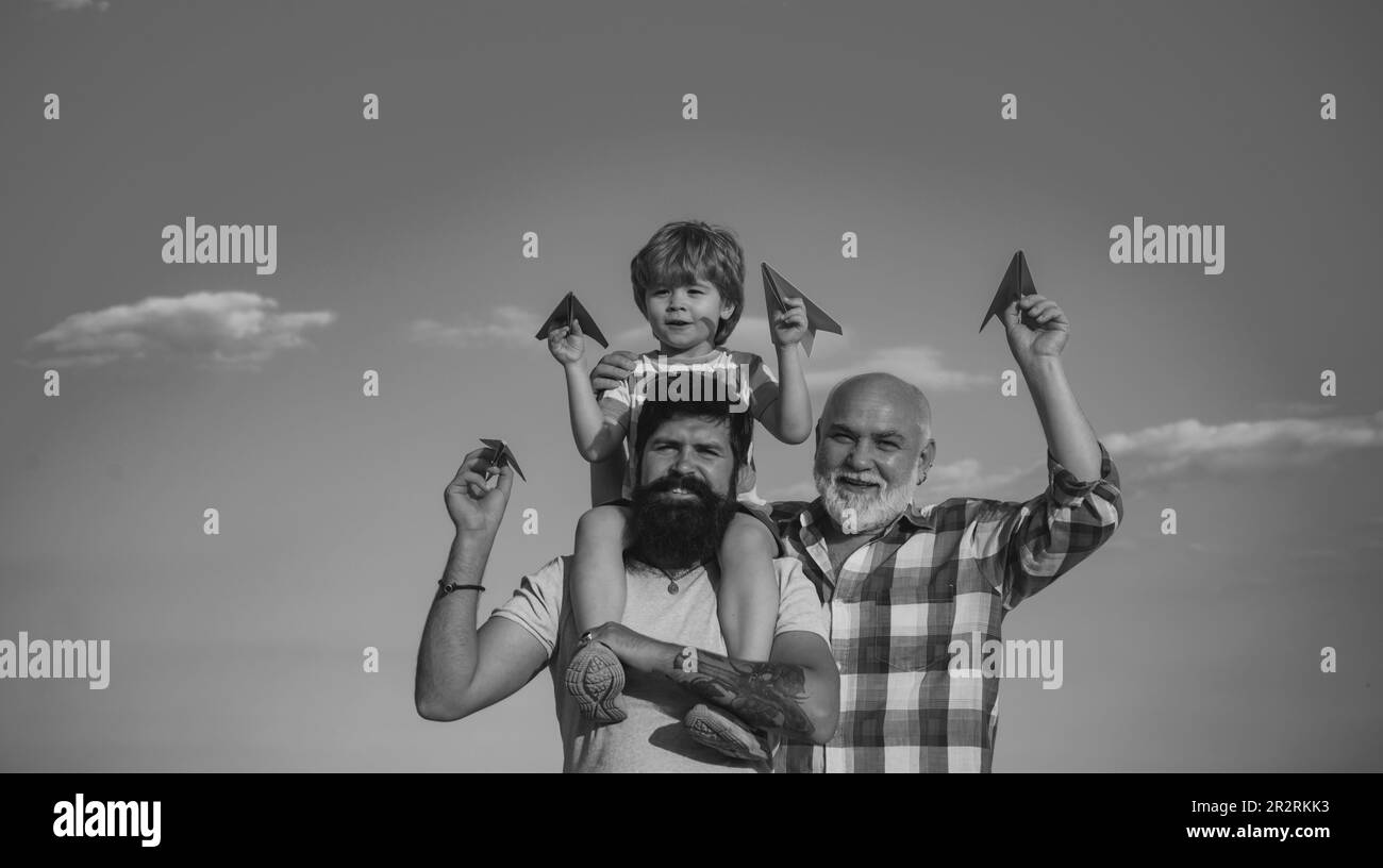 Young boy with father and grandfather enjoying together in park on blue sky background. Fathers day - grandfather, father and son are hugging and Stock Photo
