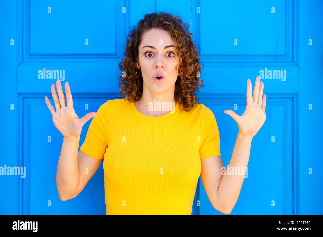 Amazed woman with opened mouth and raised hands Stock Photo