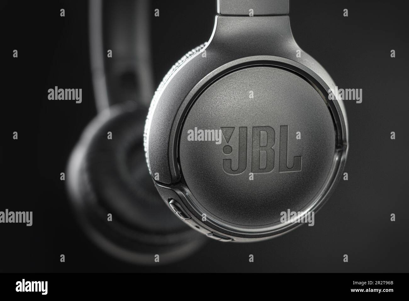 Warsaw, Poland - May 14, 2023: Black headphones on a black background. View from the side. Macro photo, close-up. Bokeh Copy space. Text brand JBL Stock Photo