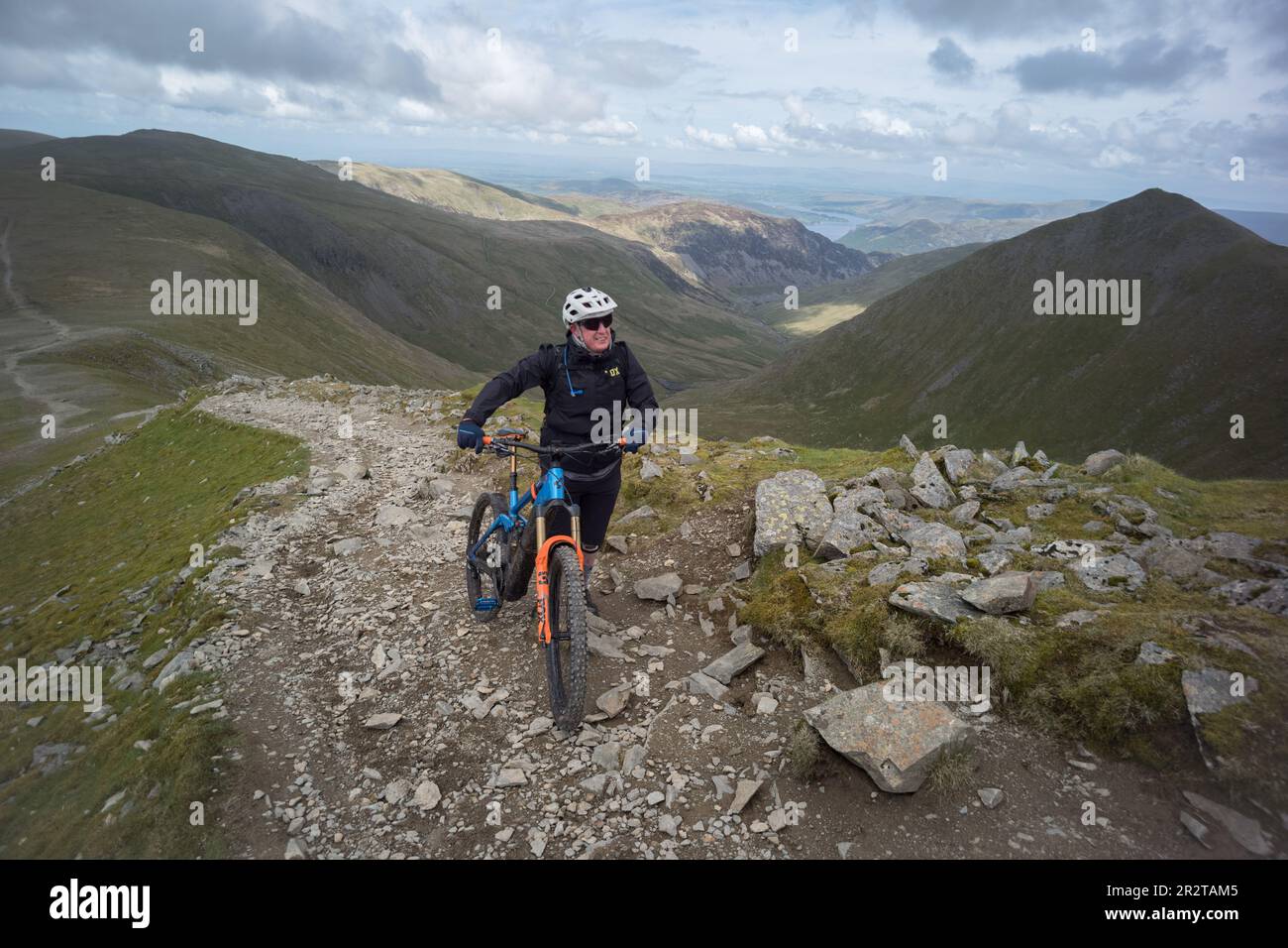 man pushing electric bike up Helvellyn Mountain, english lake district Stock Photo