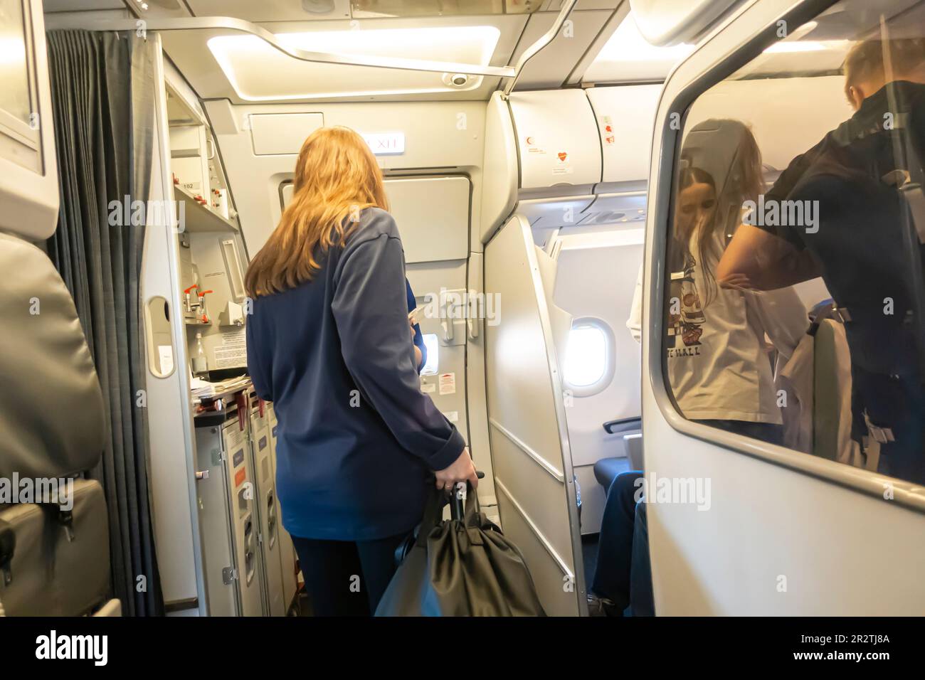 Passengers boarding Airbus A320 airplane operated by Fly Arna. back view of a female passenger entering aircraft board, through the door Stock Photo