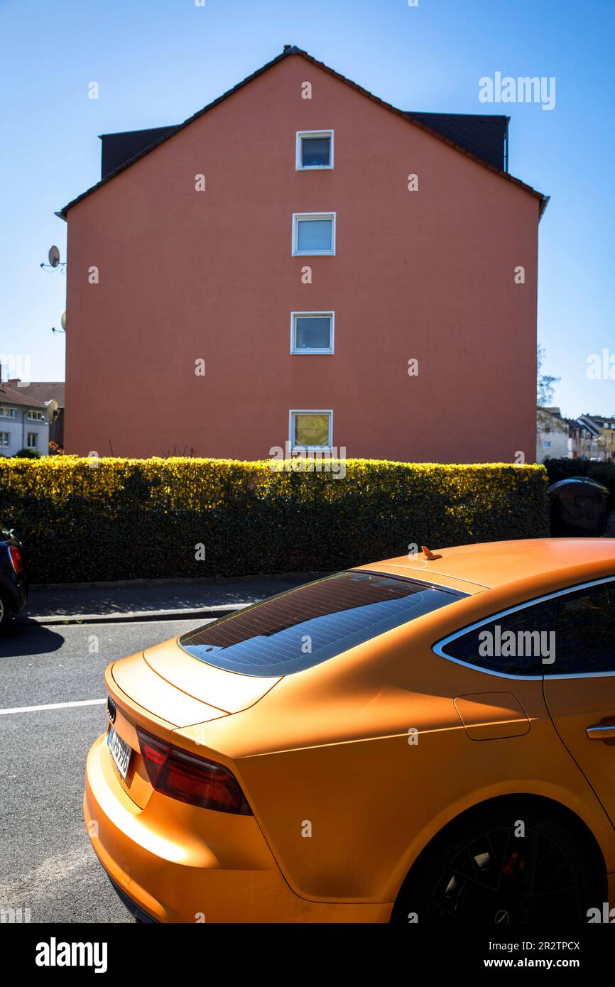 an orange Audi A5 Sportback is parked in front of a red house in the Niehl district of Cologne