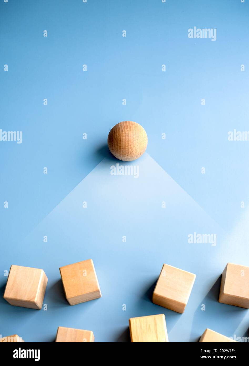 Wooden sphere stand alone at the leader position of group of wood cube blocks on blue background, vertical style. Leadership, business success, unique Stock Photo