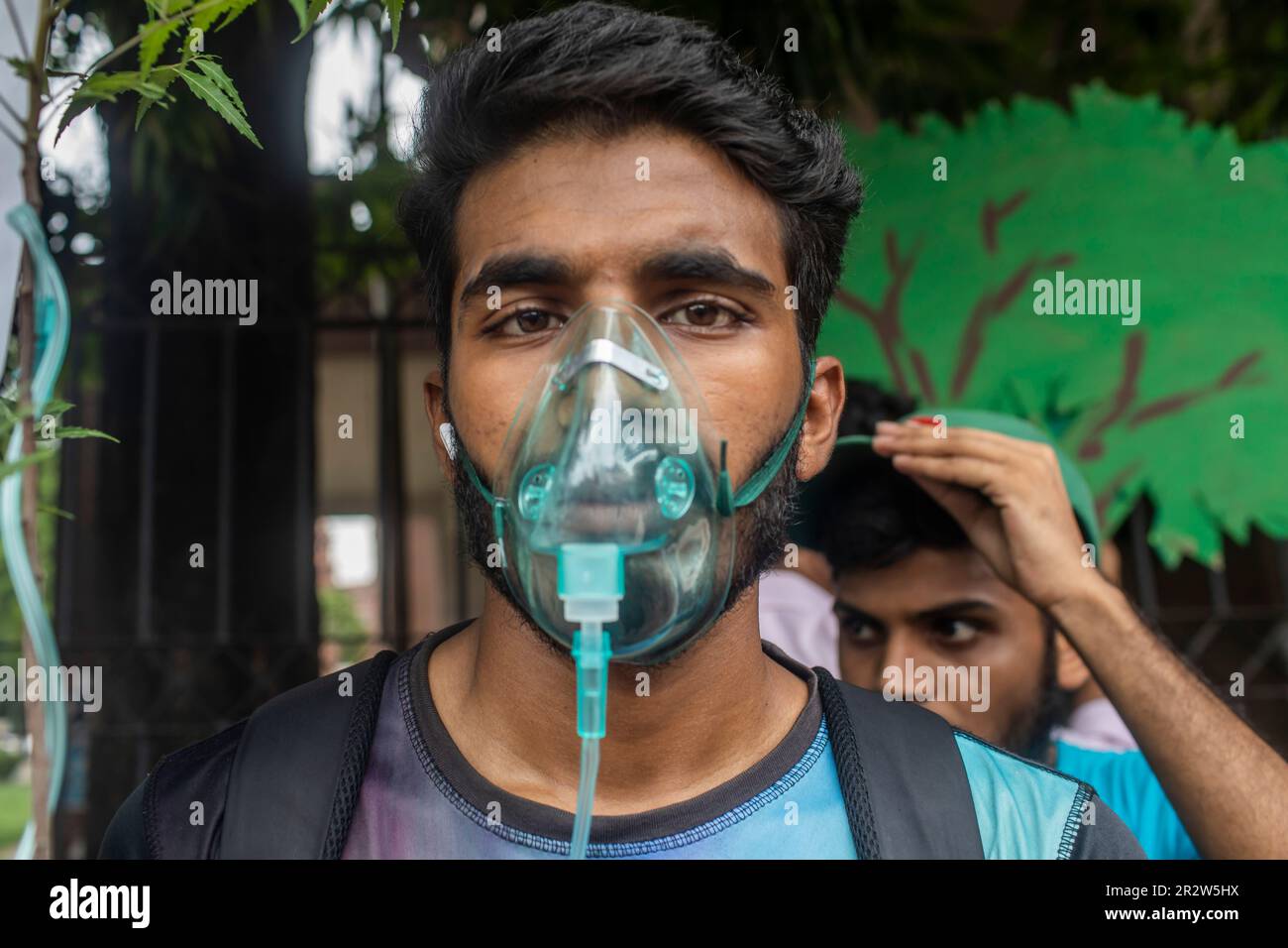 Dhaka, Bangladesh. 21st May, 2023. A protester with an oxygen mask takes part during the demonstration. Dhaka Metropolitan Police (DMP) has blocked environmental activists - under the banner of 'Saat Masjid Sarak Gach Rakkha Andalan' - from laying siege on Dhaka South City Corporation (DSCC) protesting against the felling of trees in the name of beautification of Dhanmondi's Saat Masjid Road. Credit: SOPA Images Limited/Alamy Live News Stock Photo