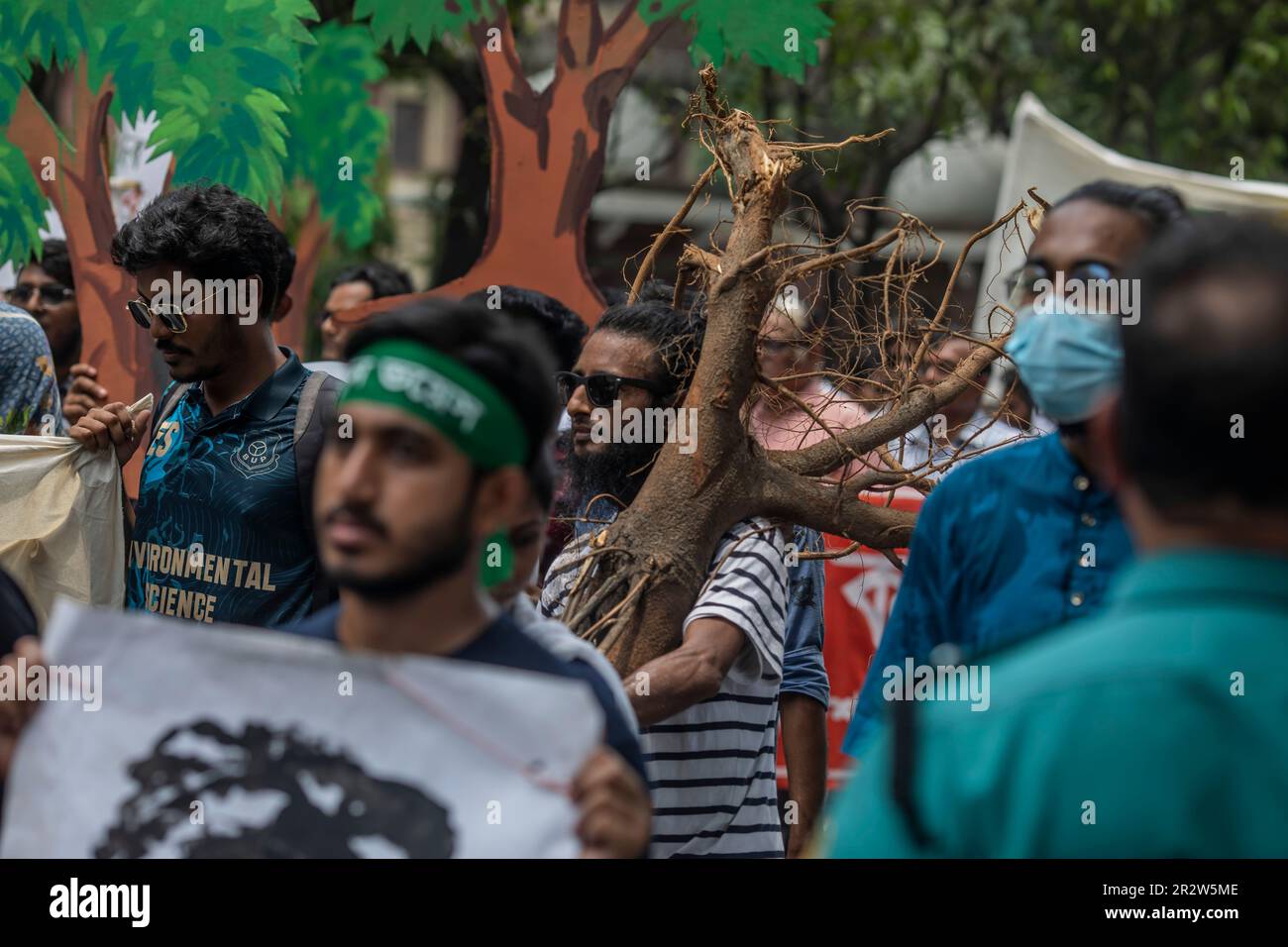 Dhaka, Bangladesh. 21st May, 2023. A protester with an oxygen mask holds a tree during the demonstration. Dhaka Metropolitan Police (DMP) has blocked environmental activists - under the banner of 'Saat Masjid Sarak Gach Rakkha Andalan' - from laying siege on Dhaka South City Corporation (DSCC) protesting against the felling of trees in the name of beautification of Dhanmondi's Saat Masjid Road. Credit: SOPA Images Limited/Alamy Live News Stock Photo