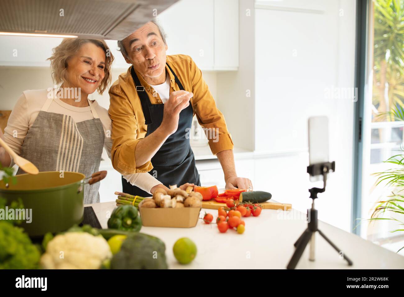 Happy aged caucasian couple famous bloggers cooking healthy dinner and ...