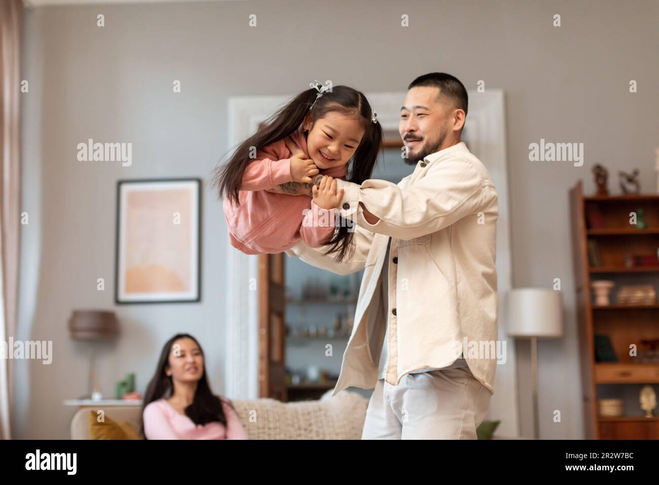 Japanese Dad Lifting Daughter In Air Enjoying Playtime At Home Stock Photo Alamy