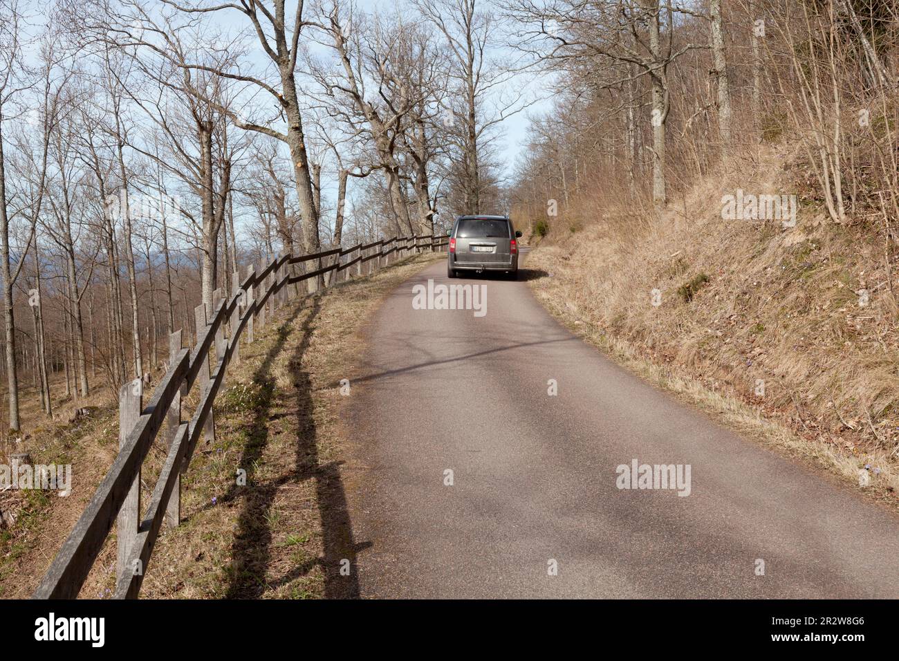 OMBERG, SWEDEN ON APRIL 09, 2015. View of a winding and narrow road. A car moves uphill. Trees, fences by the road. Editorial us Stock Photo