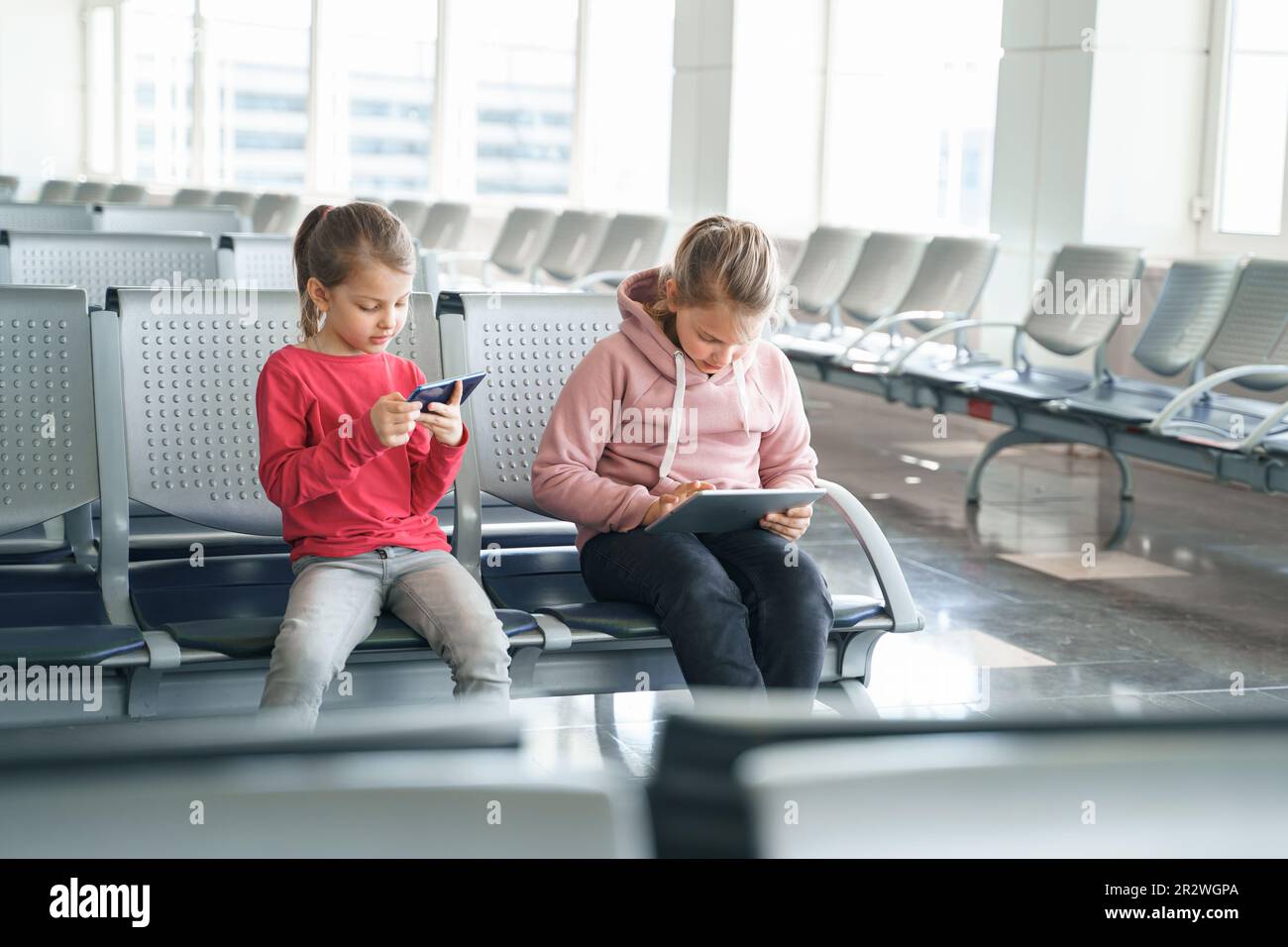 Children, kids, girls waiting for plane flight in departure hall