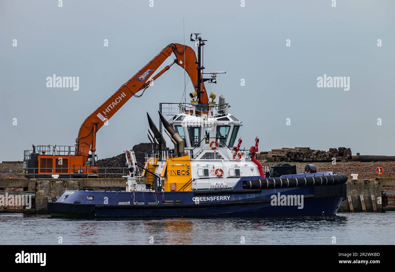 Tug boat Queensferry in Leith harbour docks with excavating digger behind, Edinburgh, Scotland