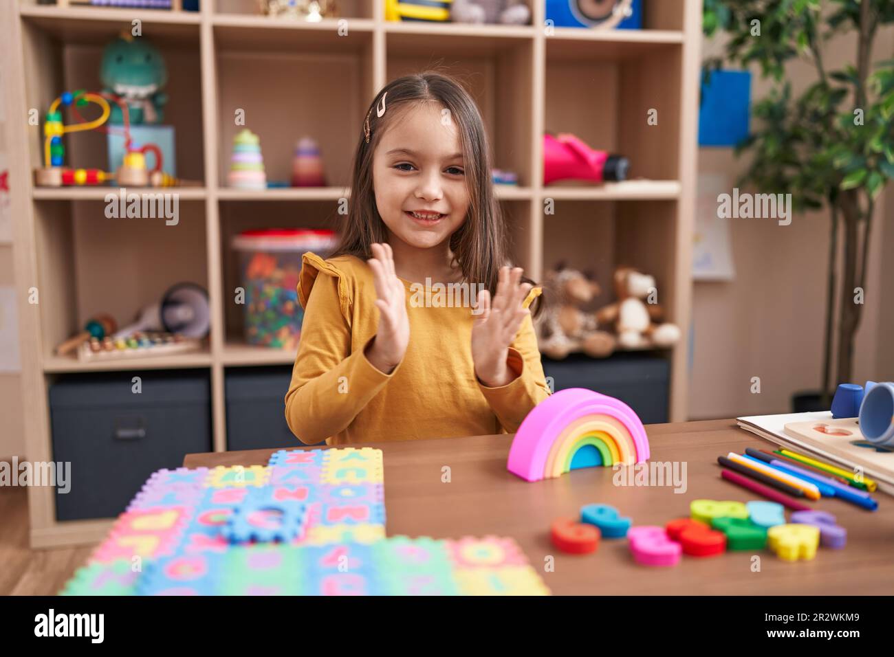 Adorable hispanic girl playing with construction blocks clapping hands ...