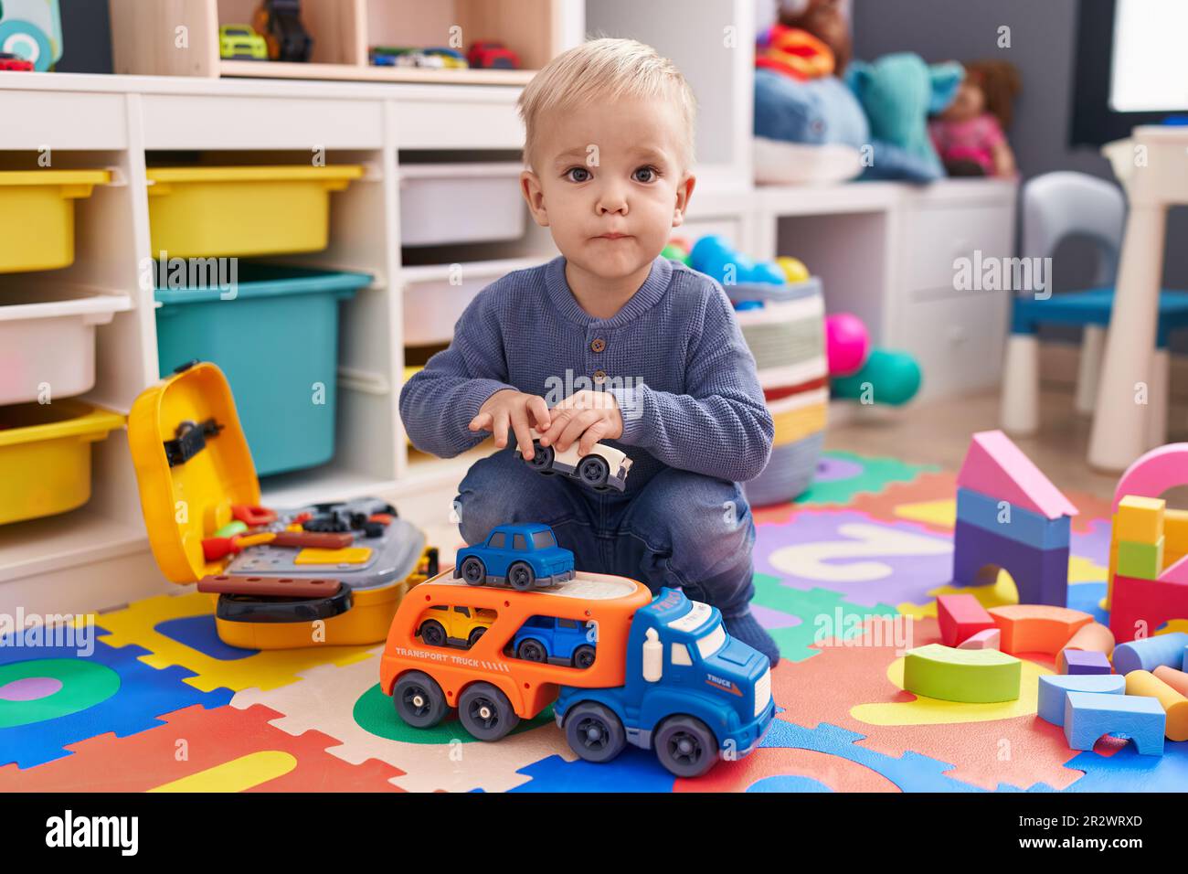 Adorable caucasian boy playing with car toy sitting on floor at ...