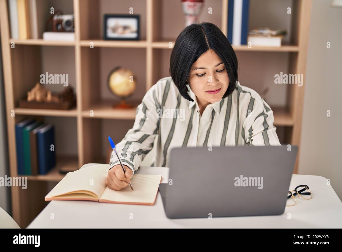 Young chinese woman studying sitting on table at home Stock Photo - Alamy
