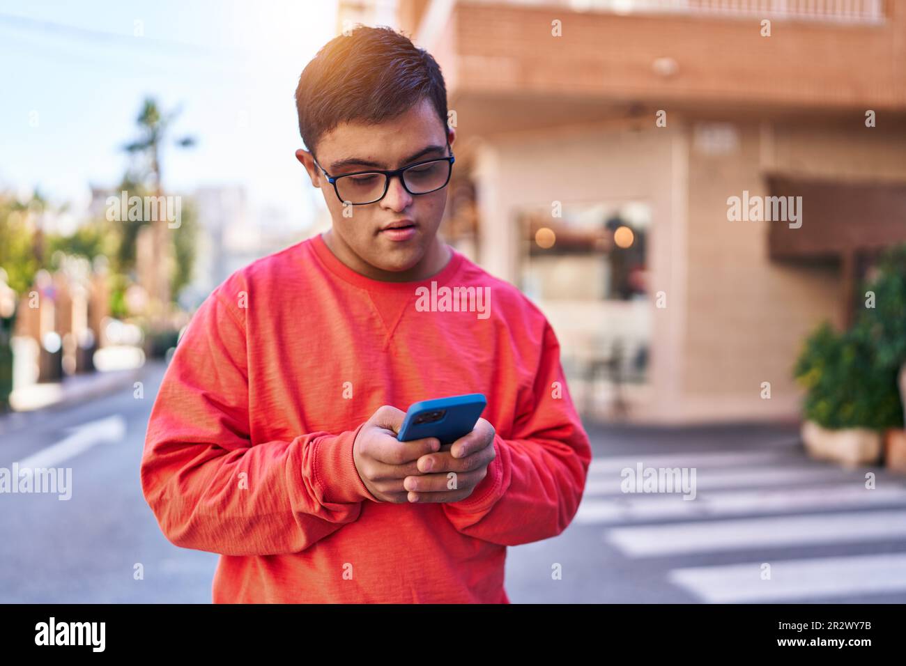 Down syndrome man using smartphone with serious expression at street Stock Photo