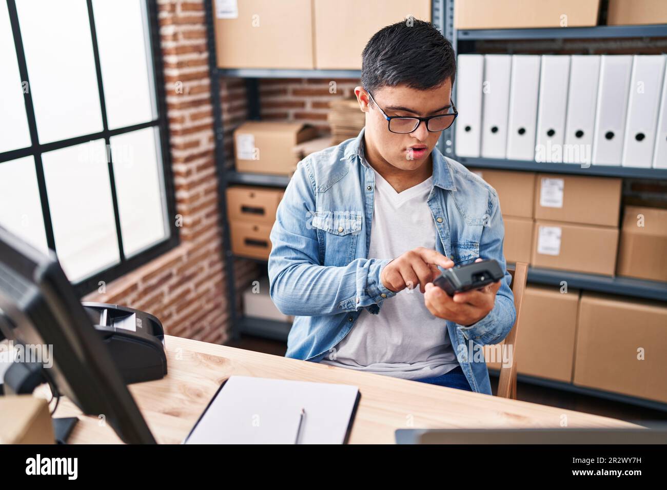 Down syndrome man ecommerce business worker using data phone at office Stock Photo