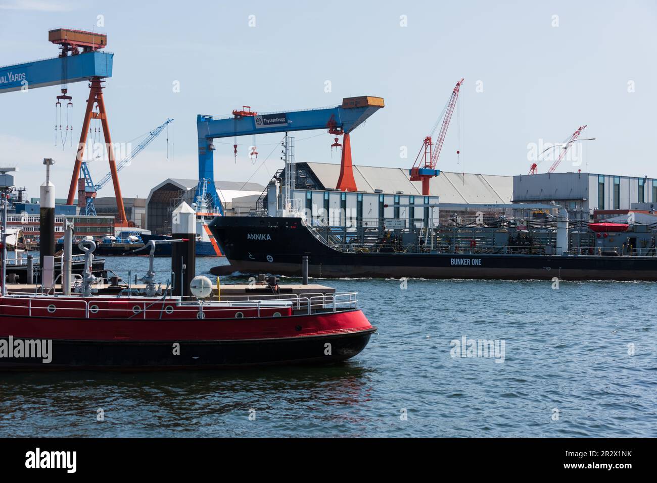 Hafenszene am kieler Schiffahrtsmuseum links vorne ein altes Feuerlöschboot, im Hintergrund die Werftanlagen mit den Portalkränen, das Tankschiff Anni Stock Photo