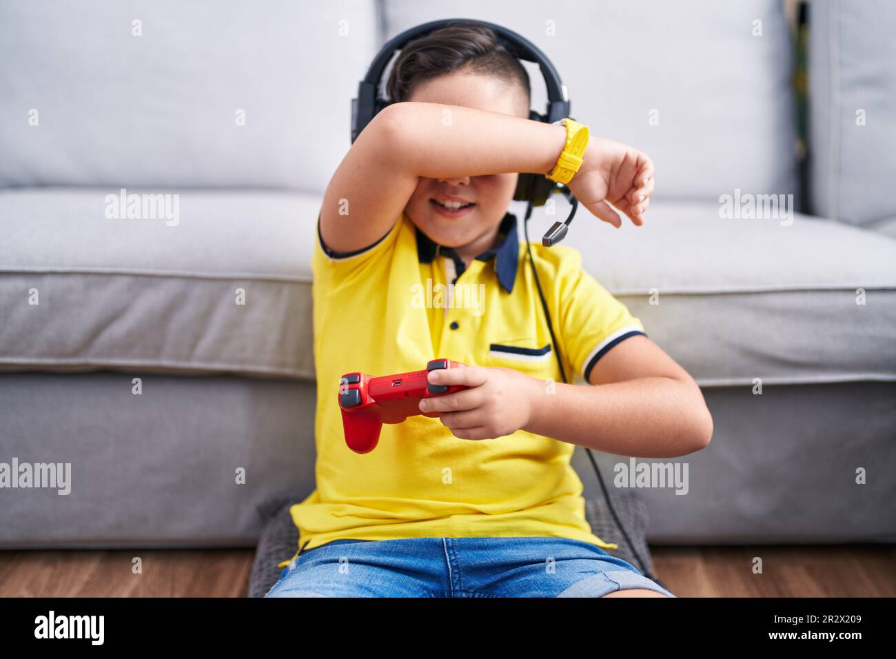 Kid Using Controller Young hispanic kid playing video game holding controller wearing ...