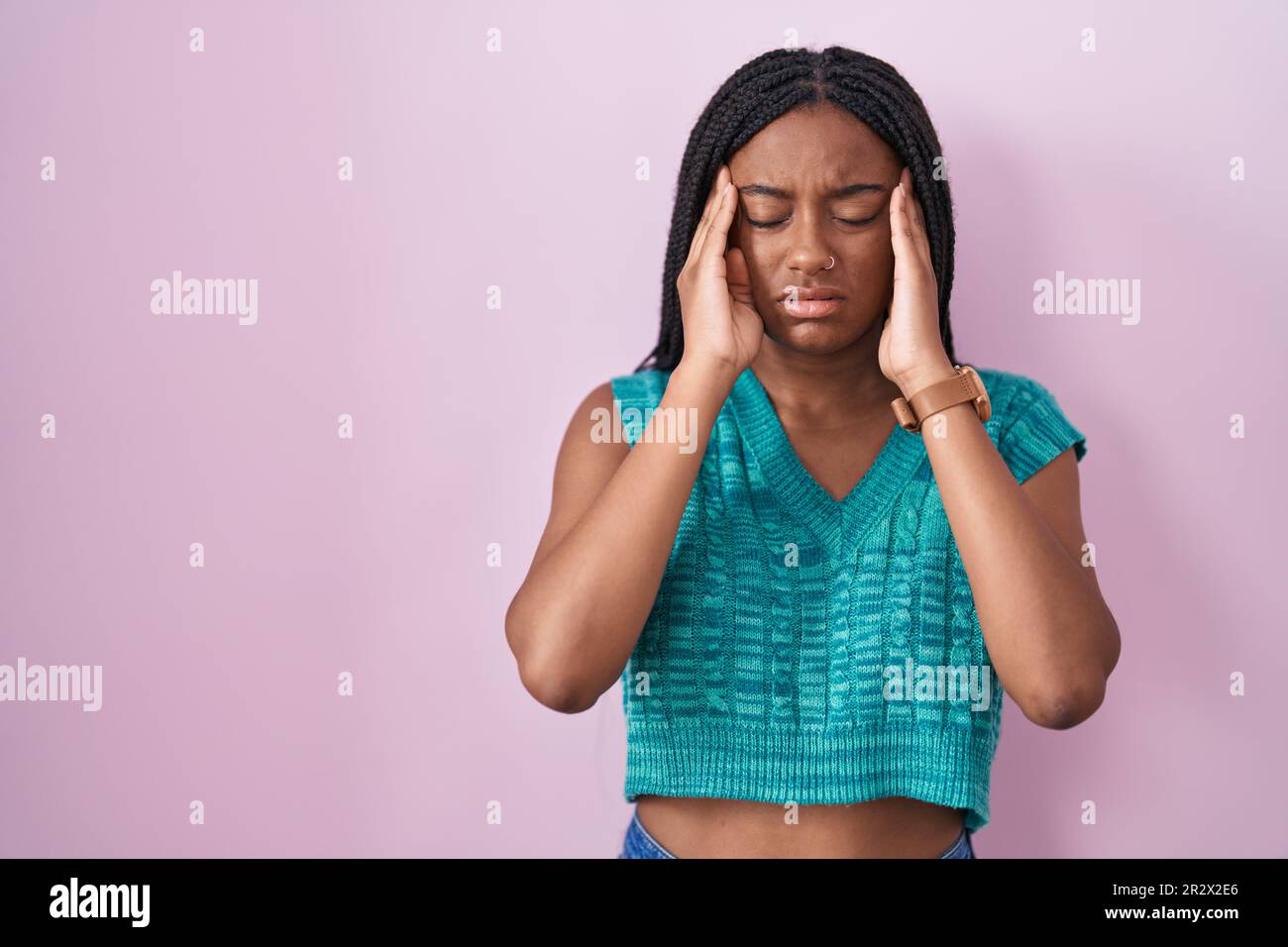Young african american with braids standing over pink background with