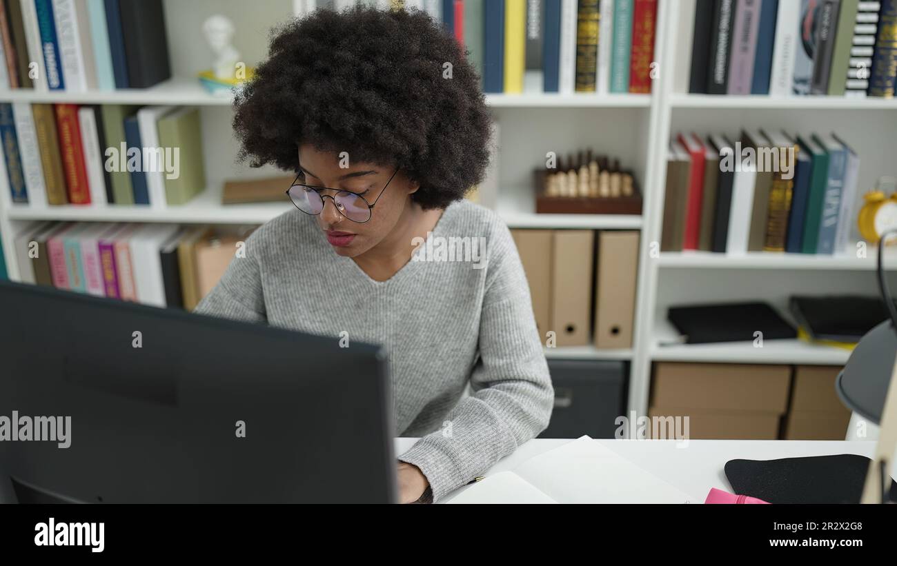 African american woman student using computer studying at library ...