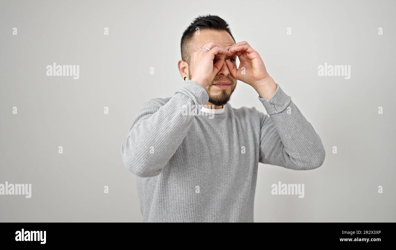 Hispanic man doing binoculars symbol with hands over isolated white background Stock Photo