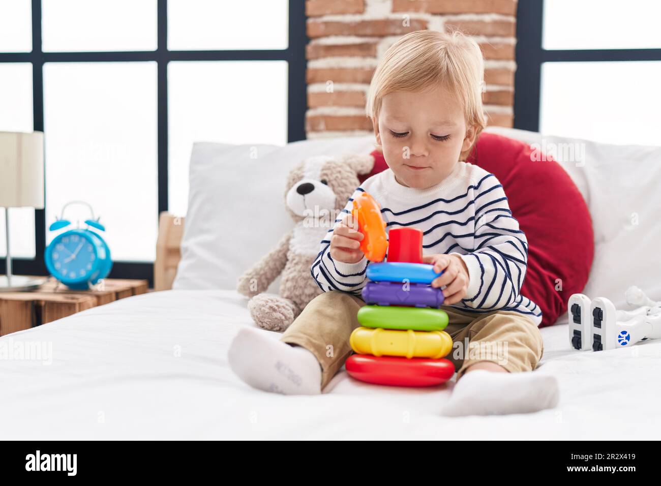 Adorable caucasian boy playing with hoops game sitting on bed at ...