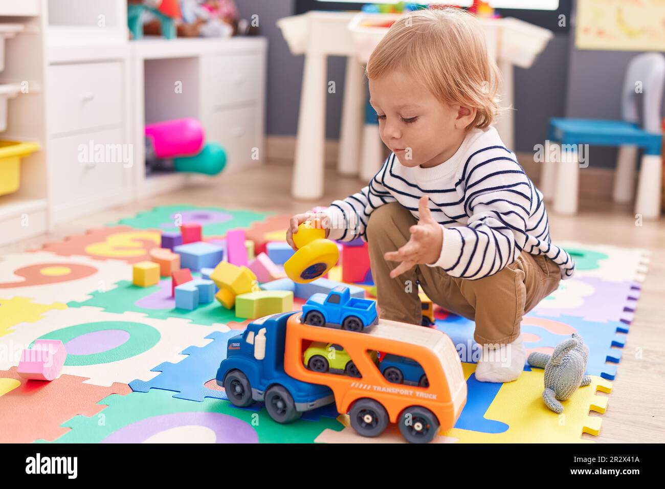 Adorable caucasian boy playing with car toy sitting on floor at ...