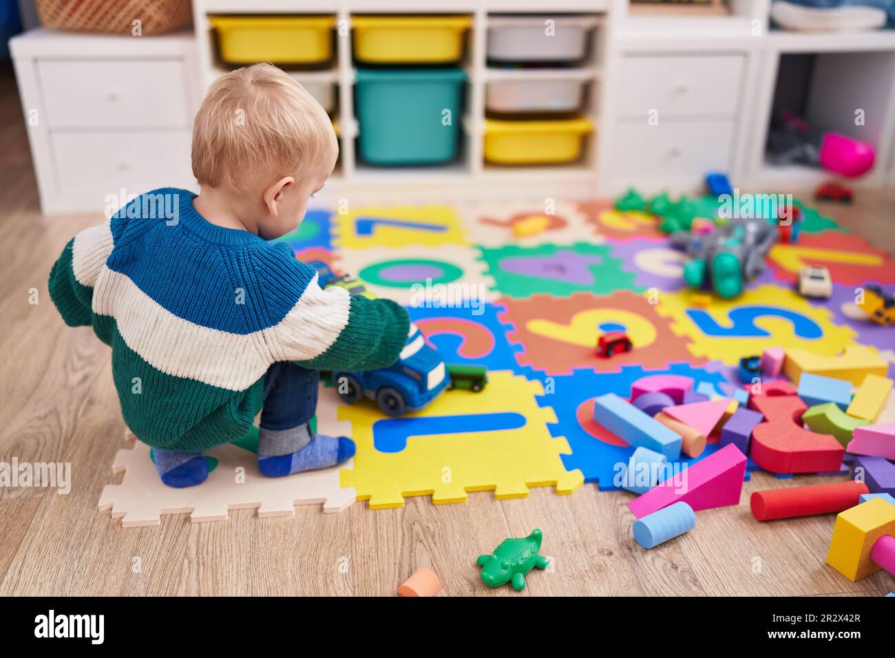 Adorable caucasian boy playing with car toy sitting on floor at ...