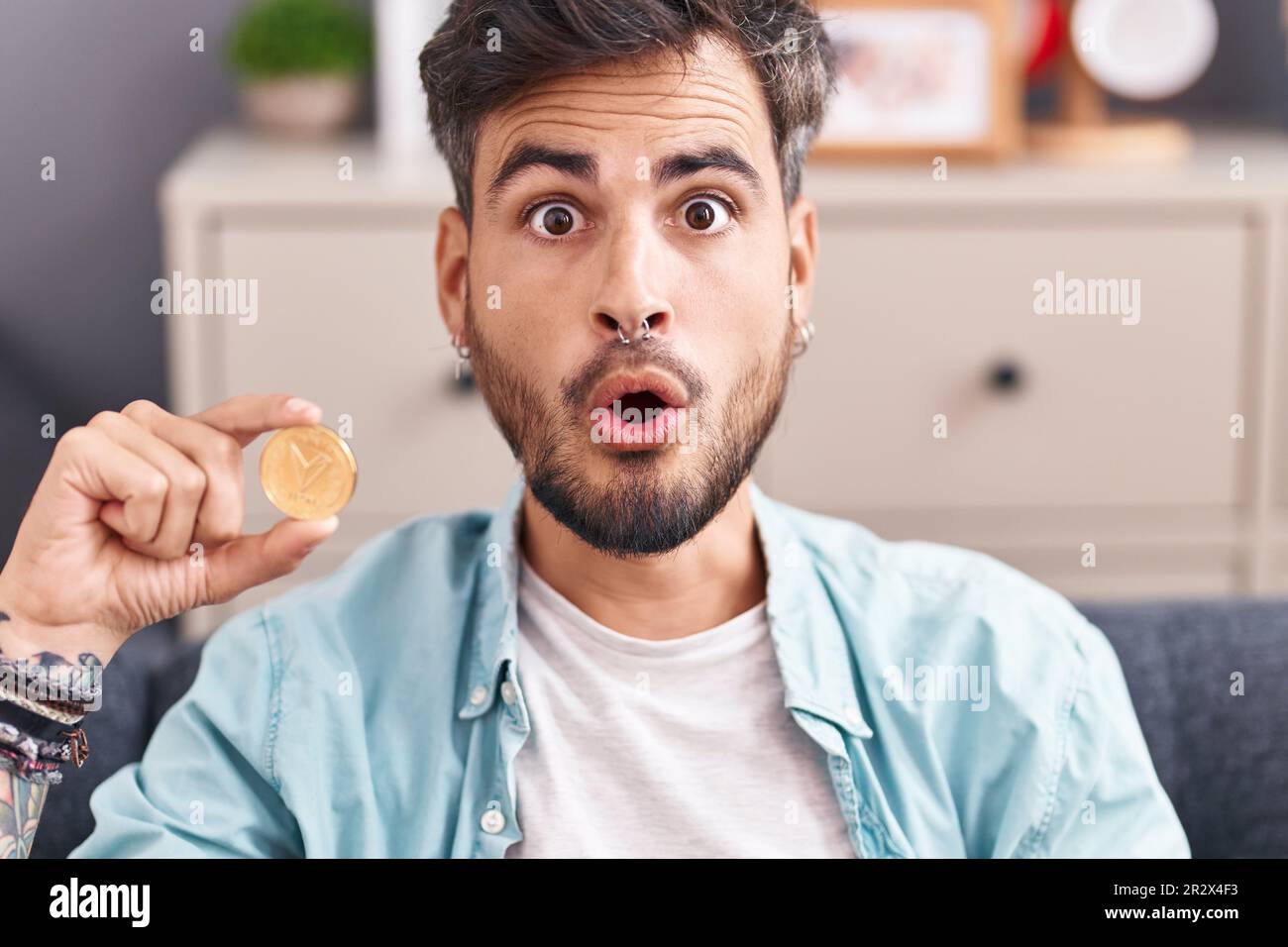 Young hispanic man with tattoos holding tron cryptocurrency coin scared and  amazed with open mouth for surprise, disbelief face Stock Photo - Alamy