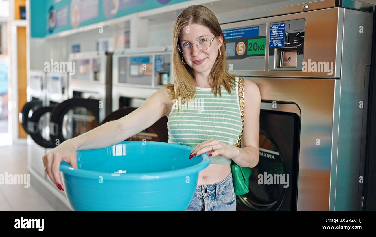 Young blonde woman smiling confident holding empty basket at laundry ...