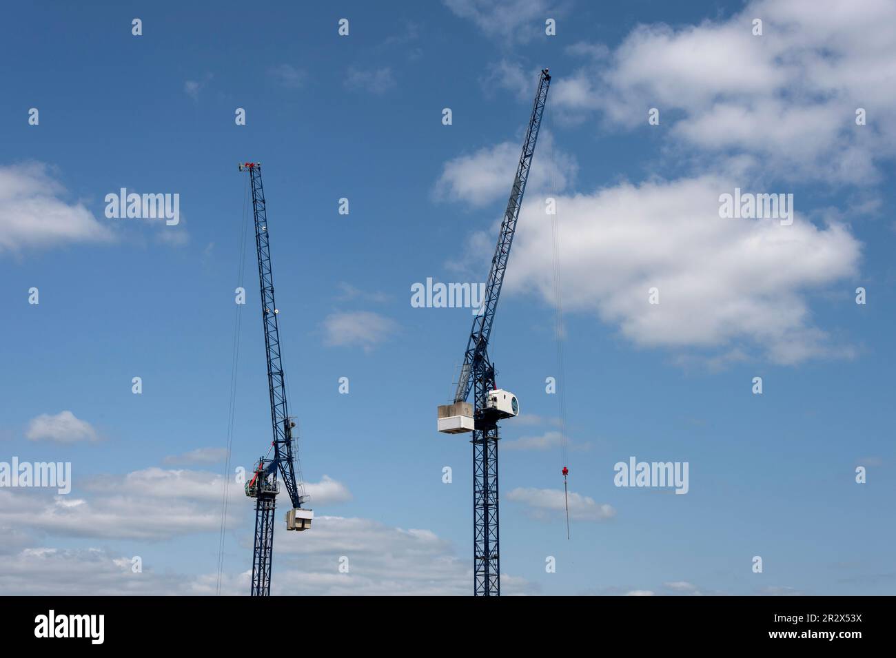 Two tower cranes against a blue sky Stock Photo