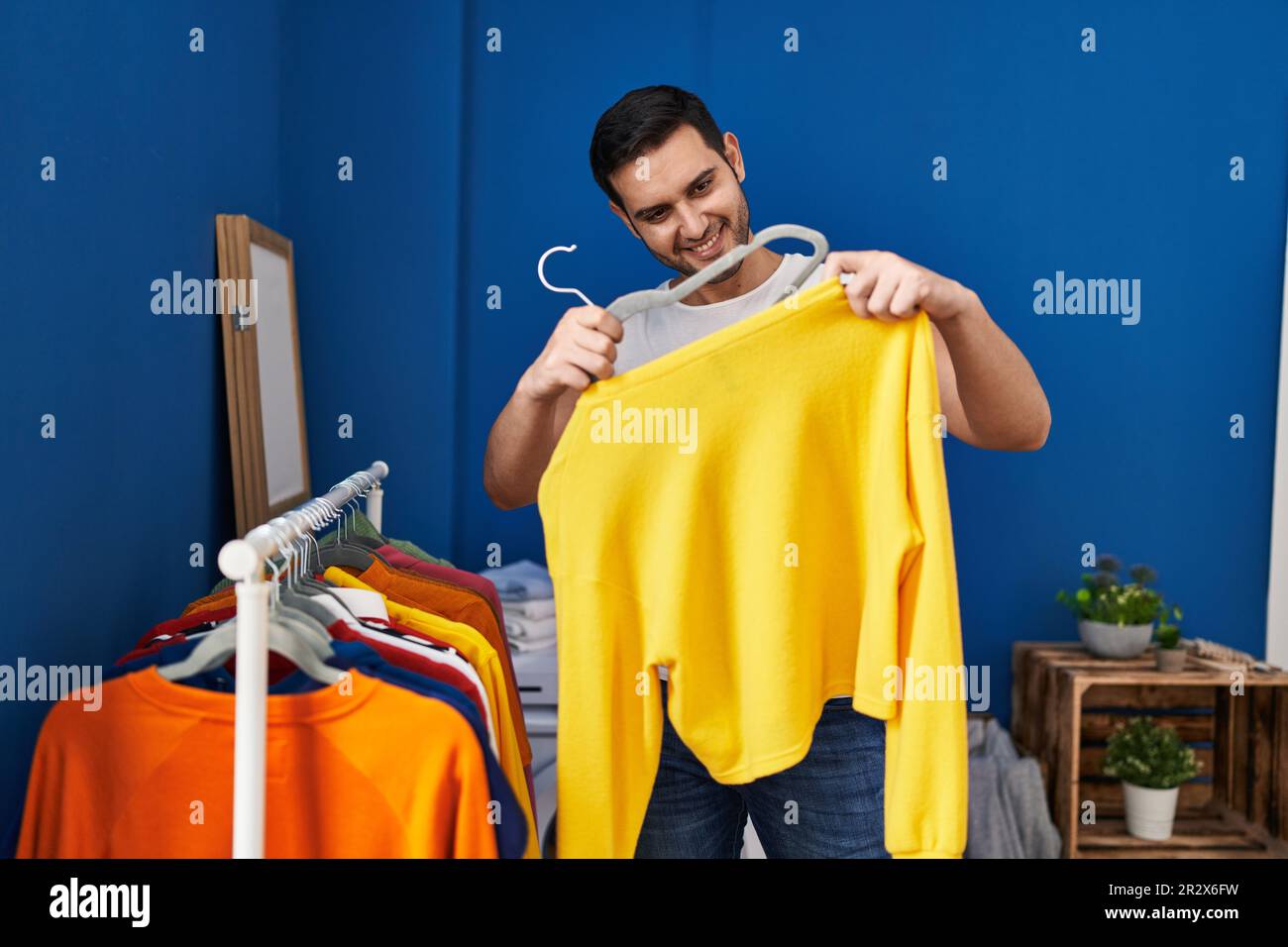 Hispanic Rack Young hispanic man putting clothes on clothes rack at laundry room ...