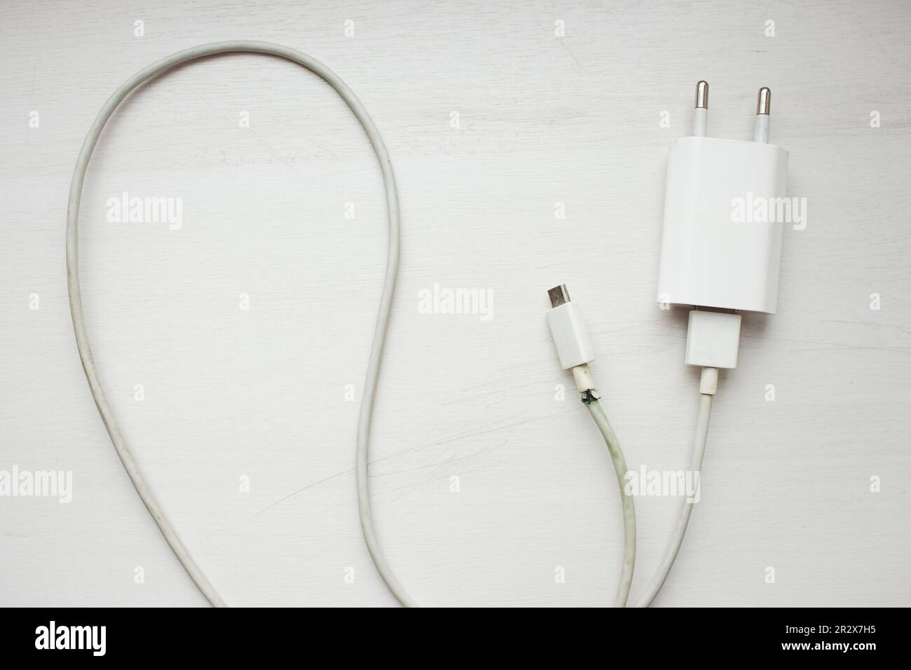 Electric plug on white background. Broken power cord with charger. Broken usb cord. Smartphone device. Cable for mobile phone. Stock Photo