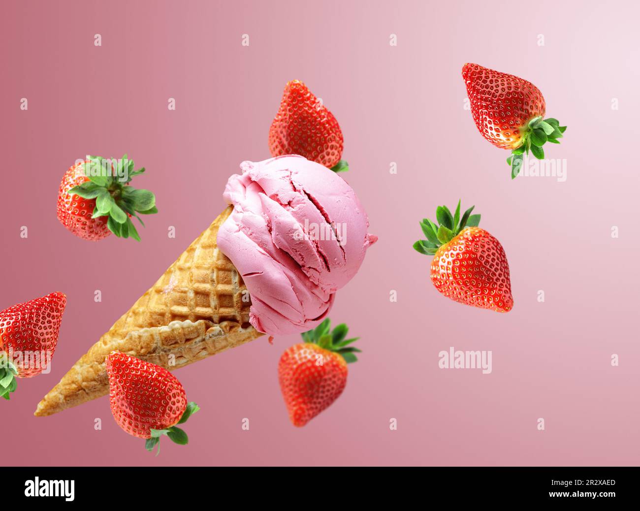 Strawberry ice cream in a waffle cone with falling fresh berries on a ...