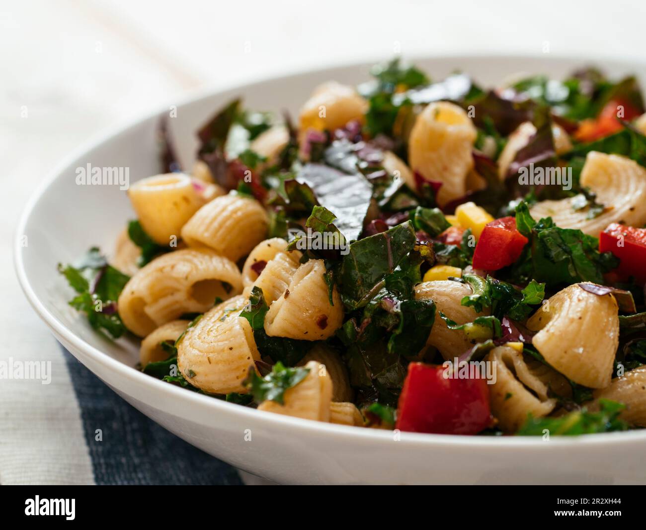 Bowl with a vegan home made kale pasta salad using the heirloom variety 'Red Russian'. Stock Photo