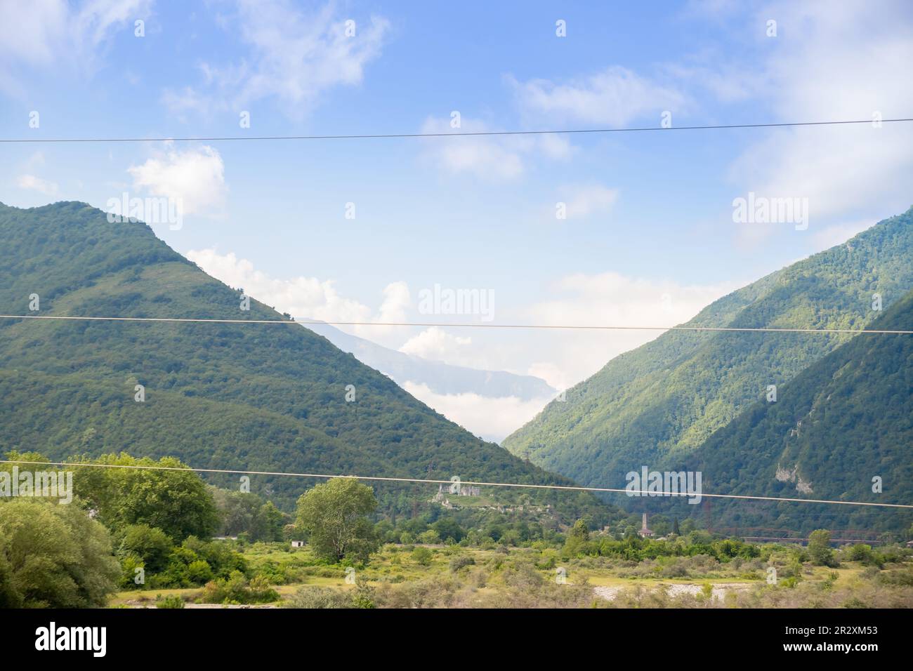 Colorful view to sunlit green mountain valley with forest and river ...