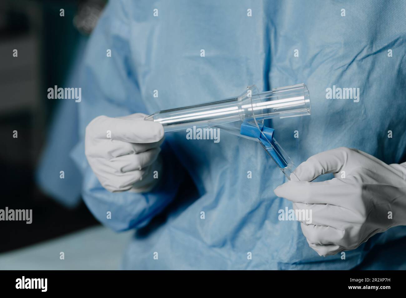 A surgeon in latex gloves and a blue uniform holds a special proctological instrument Stock Photo