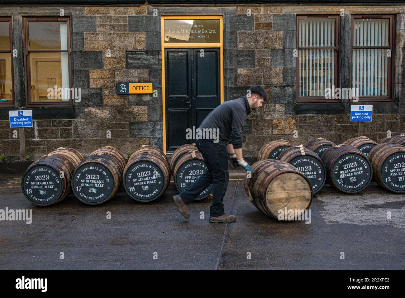 Employee rolling a whisky cask at the Springbank whisky distillery