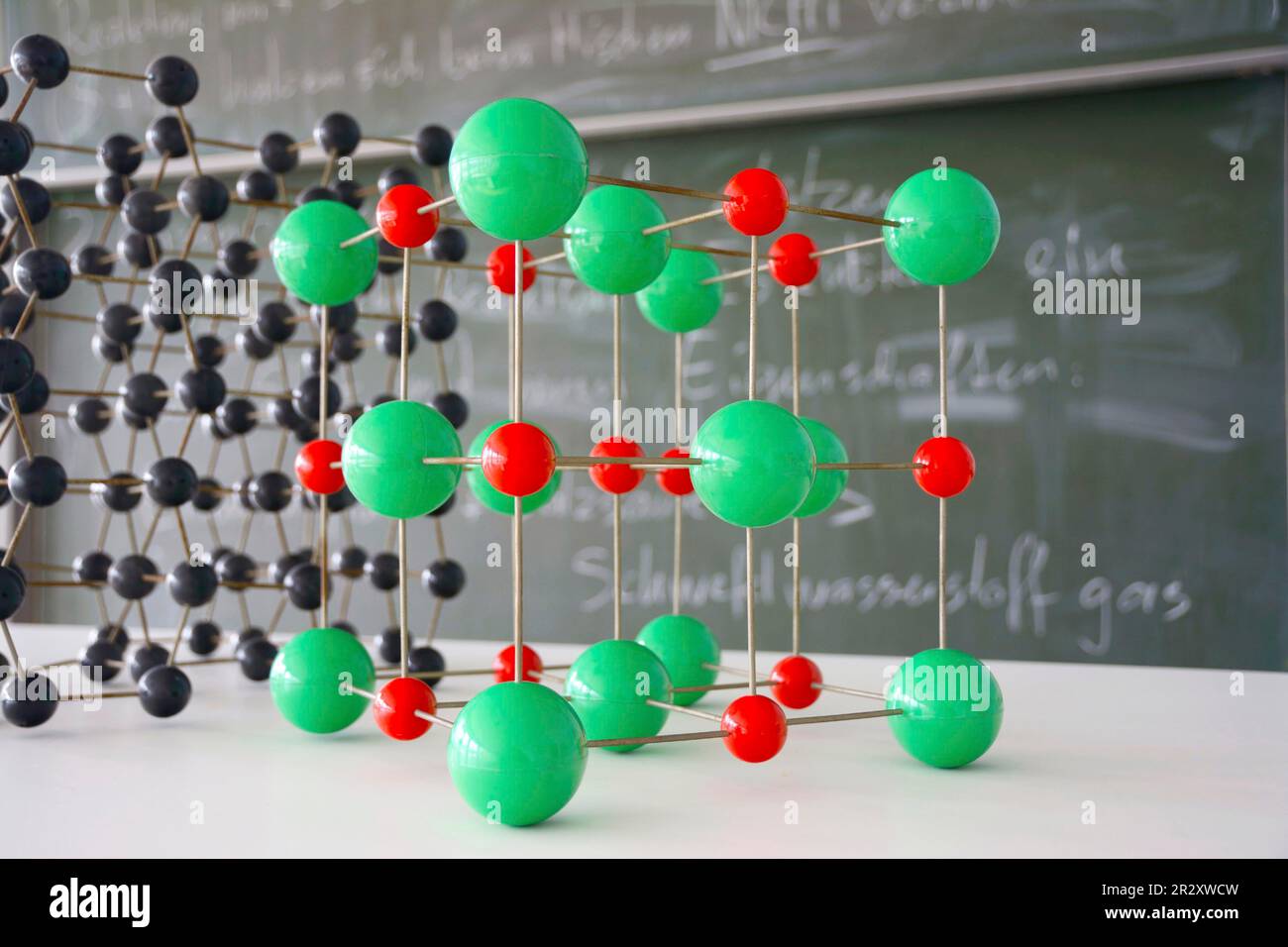 Atomic model in chemistry classroom with chalkboard in background Stock Photo