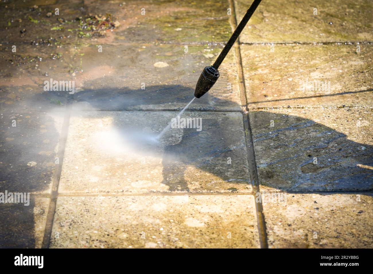 Pressure washer (Power jet ) cleaning off grime from a patio pavestone Stock Photo