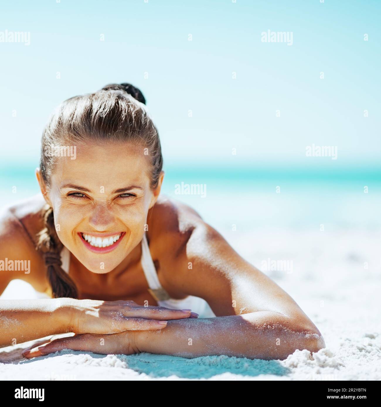 smiling young woman in swimsuit laying on sandy beach Stock Photo Alamy