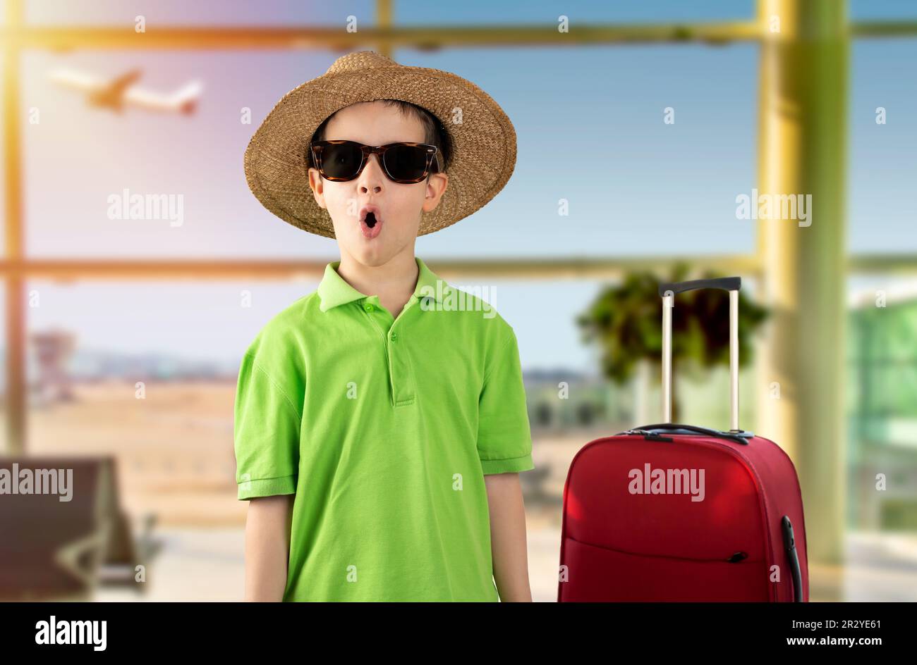 Child on vacation wearing green t-shirt hat sunglasses at airport, afraid and shocked with surprise expression, fear and excited face. Stock Photo