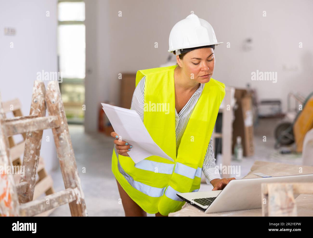 Focused female civil engineer using laptop at construction site Stock Photo