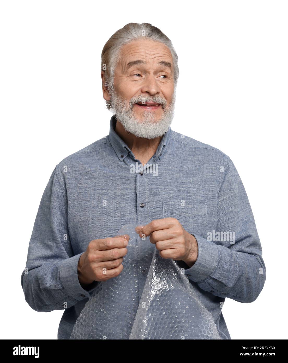 Happy senior man popping bubble wrap on white background. Stress relief