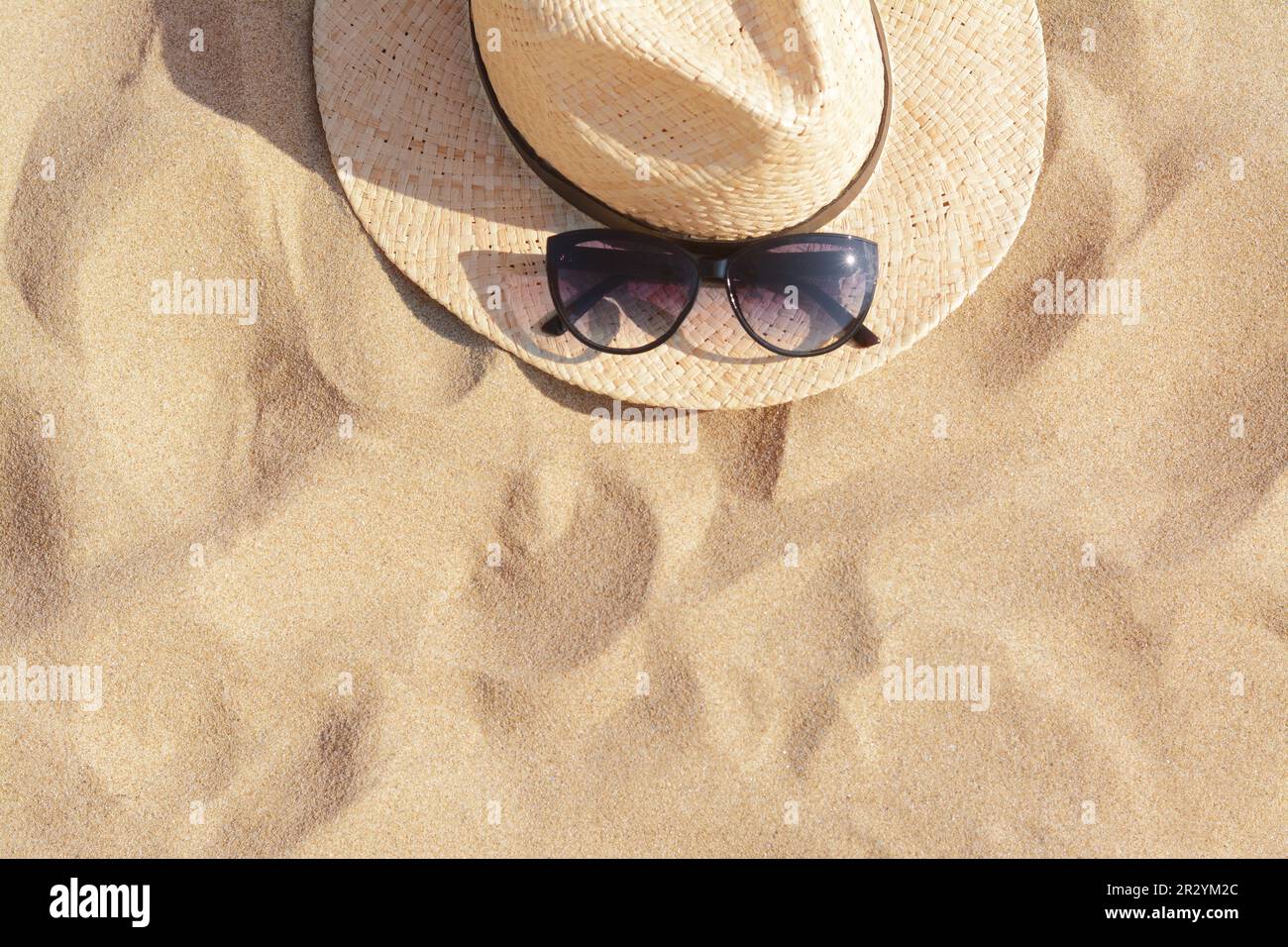 Hat with beautiful sunglasses on sand, top view. Space for text Stock ...