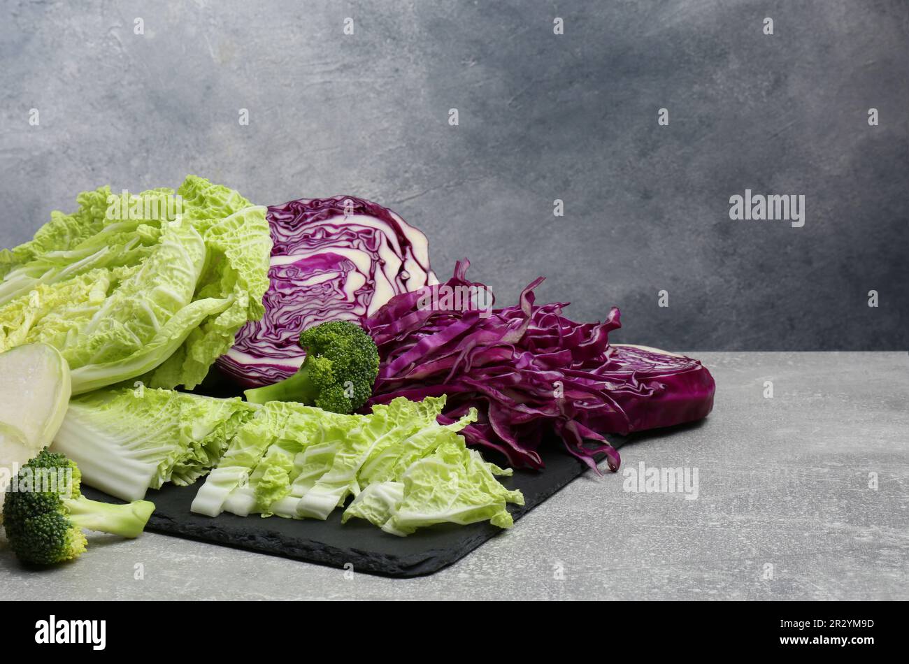 Different types of cut cabbage on light grey table, space for text ...