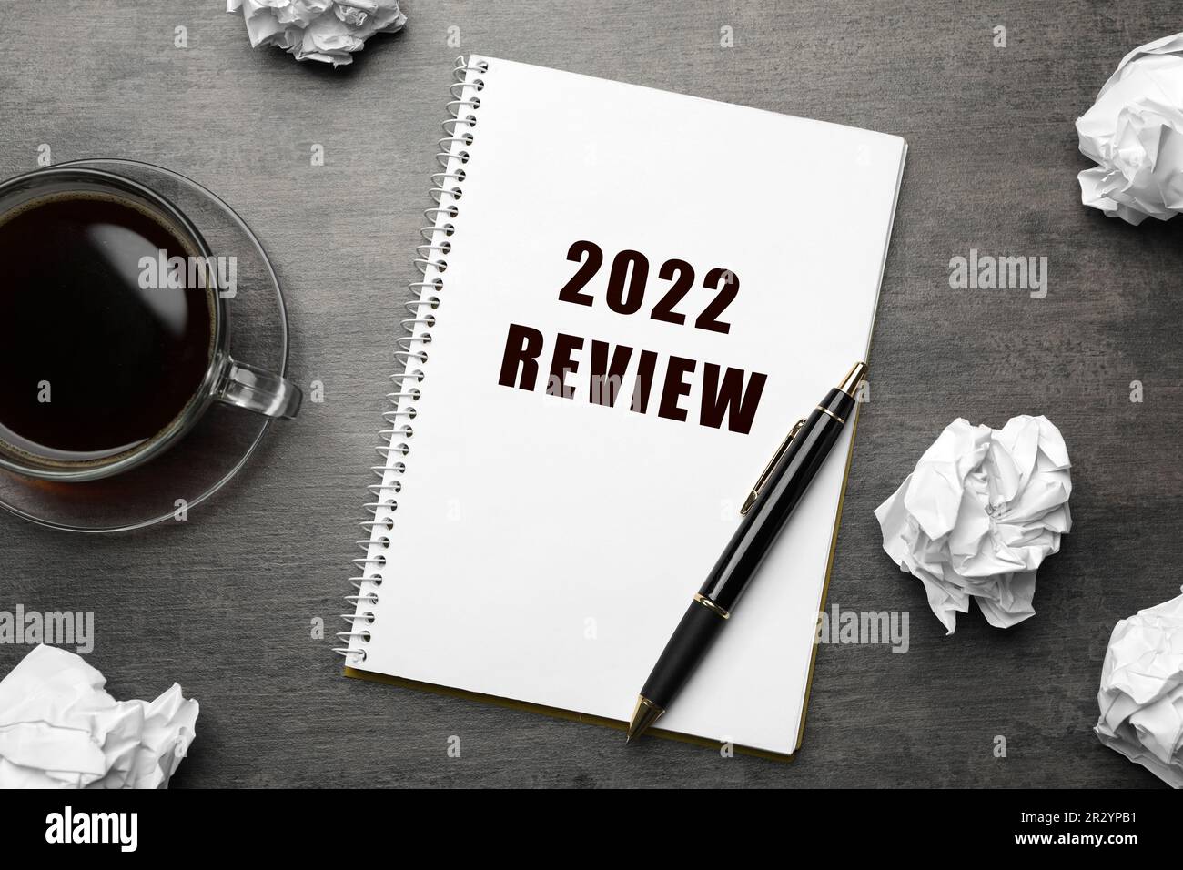Text 2022 Review written in notebook, pen, cup of coffee and crumpled paper balls on grey table, flat lay Stock Photo