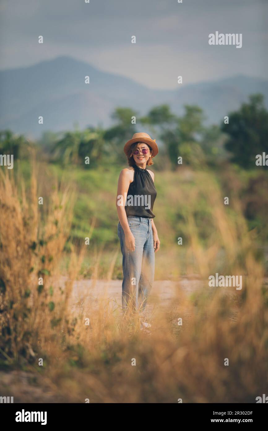 asian woman wearing straw hat standing outdoor toothy smiling with happiness face Stock Photo