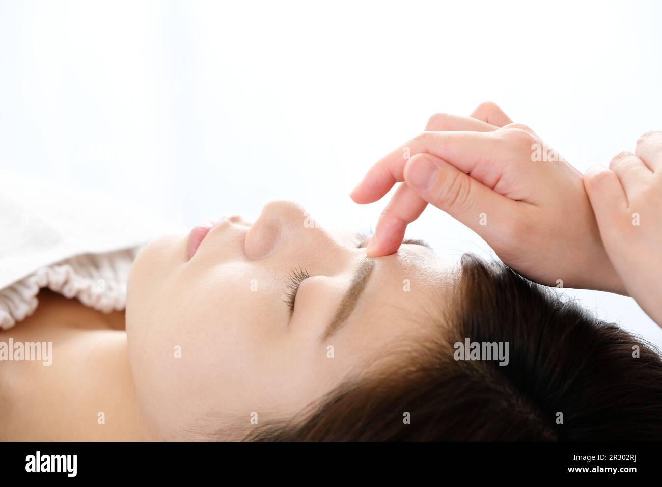 Woman receiving acupressure between the eyes at an acupuncture clinic Stock Photo